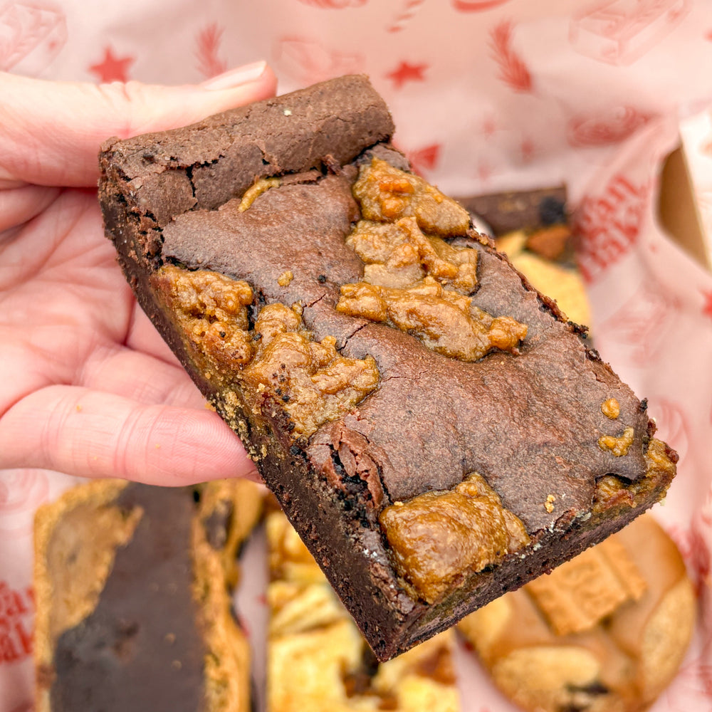 Brownie with cookie pieces held over a red and pink branded paper