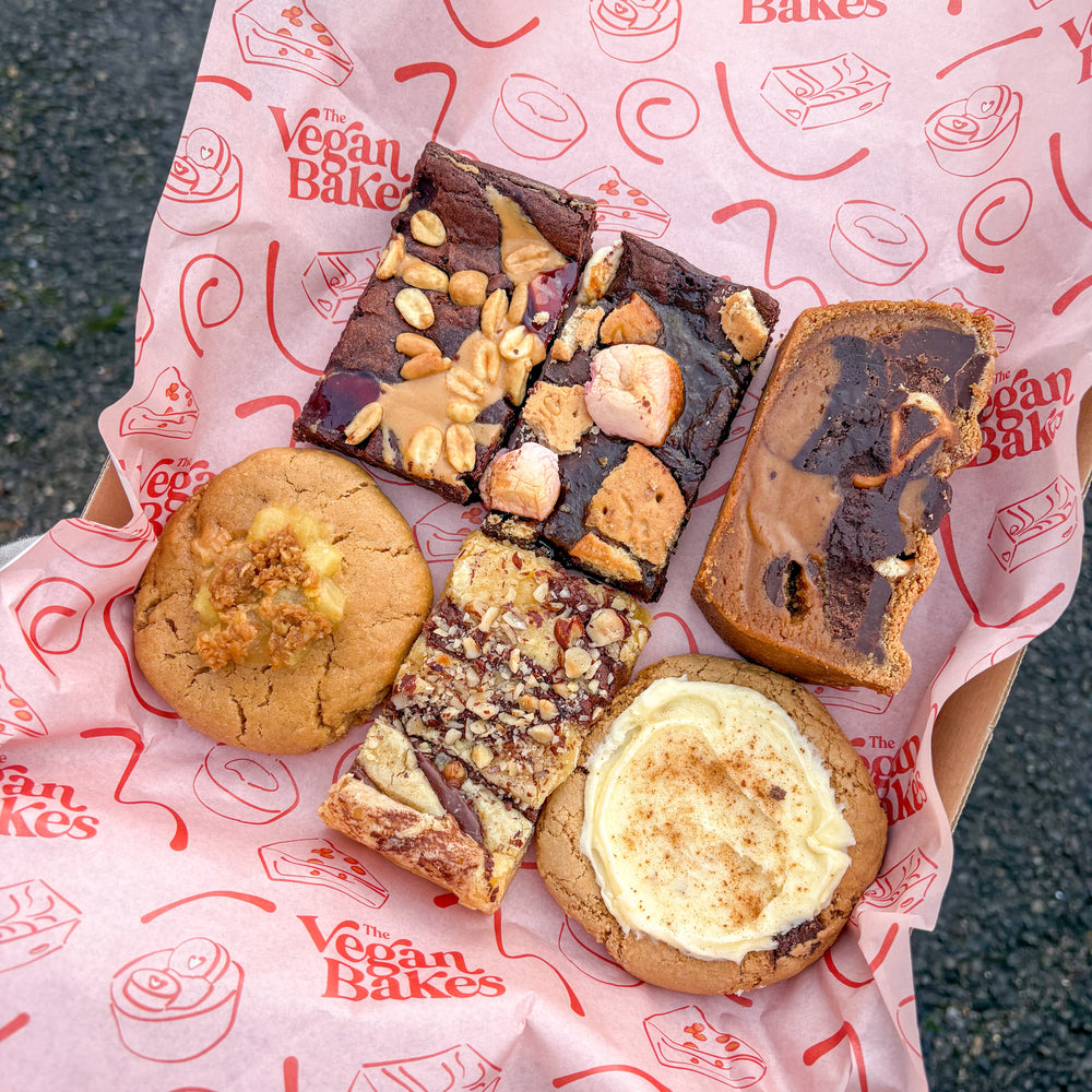 Assorted vegan baked goods on a 'Vegan Bakes' branded paper.