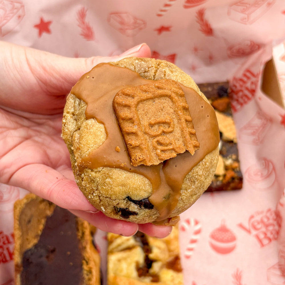 Hand holding a cookie with a visible brand name against a branded paper background